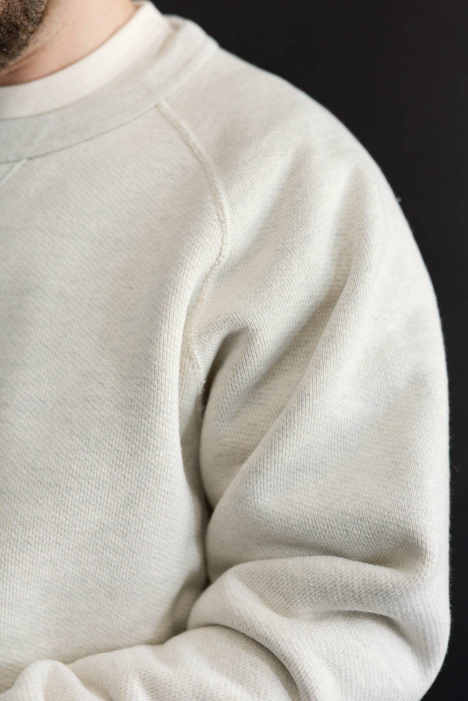 Close-up of the right shoulder and sleeve of a cream sweatshirt on a 5'9
