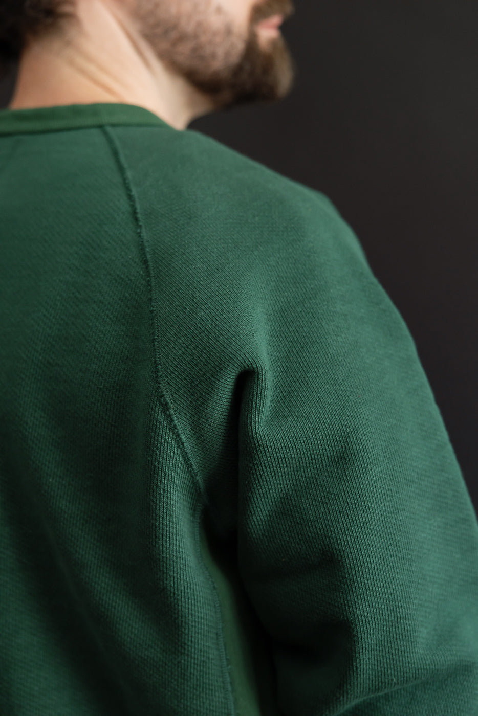 Close-up of the back and shoulder of a green sweatshirt showing ribbed fabric texture.