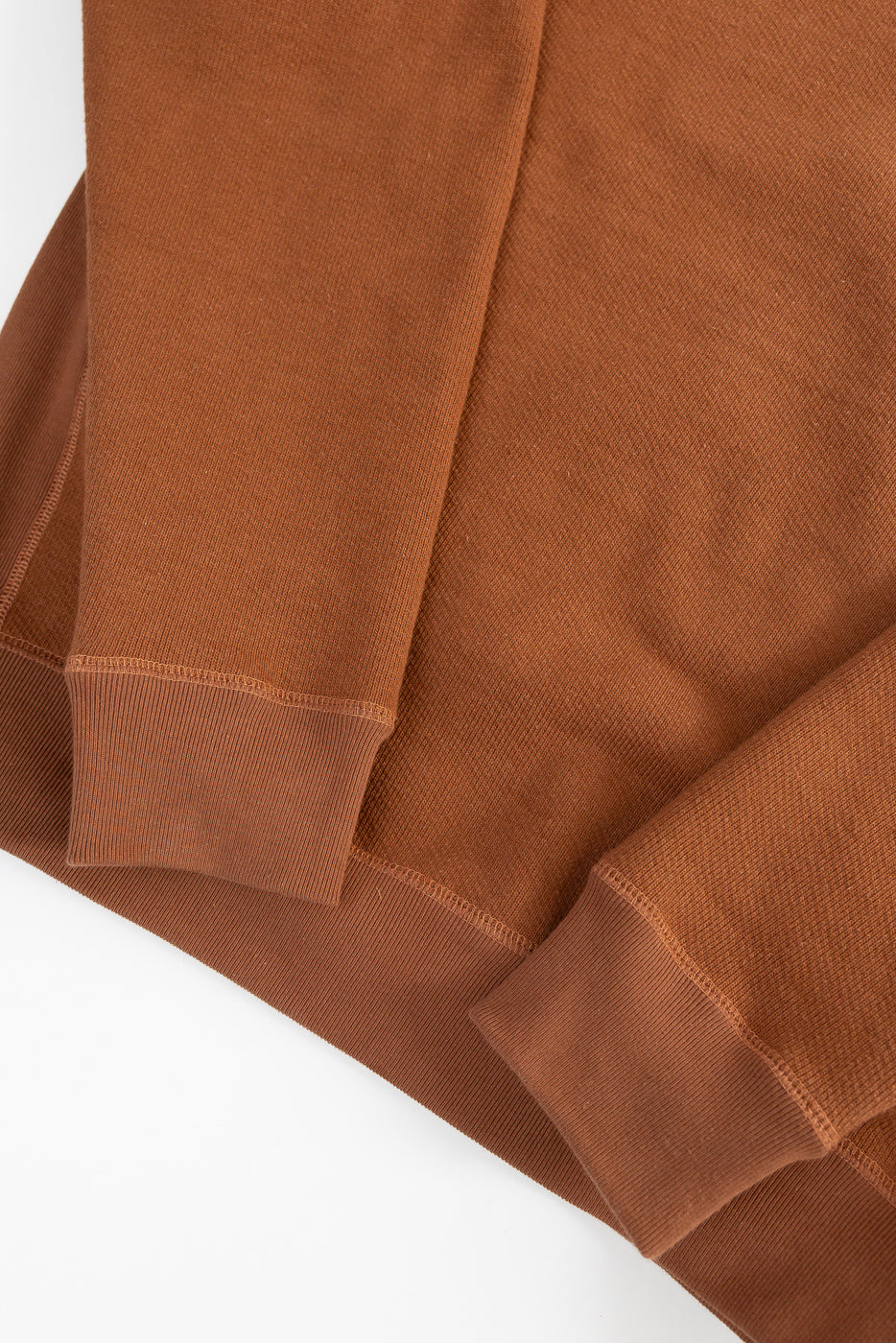 Close-up of Wonder Looper rust French terry crewneck pullover cuff and hem details, front view.