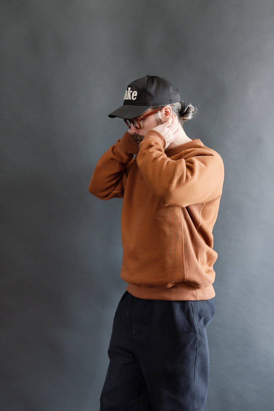 Male model 5'9 165lbs athletic build in rust crewneck pullover, right-side view, upper body