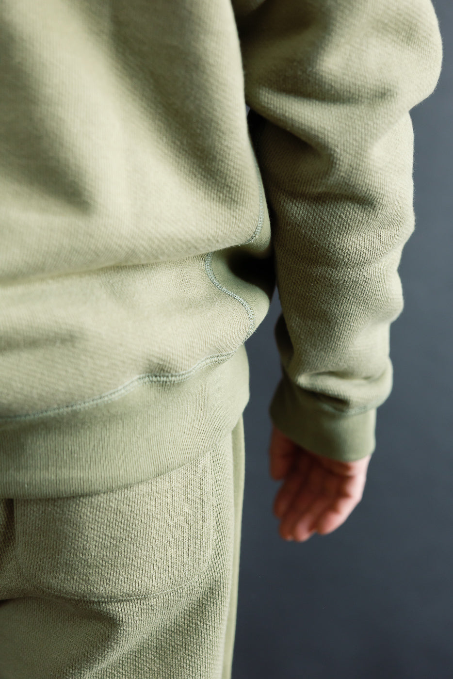 Close-up of men's Wonder Looper sage crewneck pullover hem and sleeve, side view, textured heavyweight French terry, model 5'9