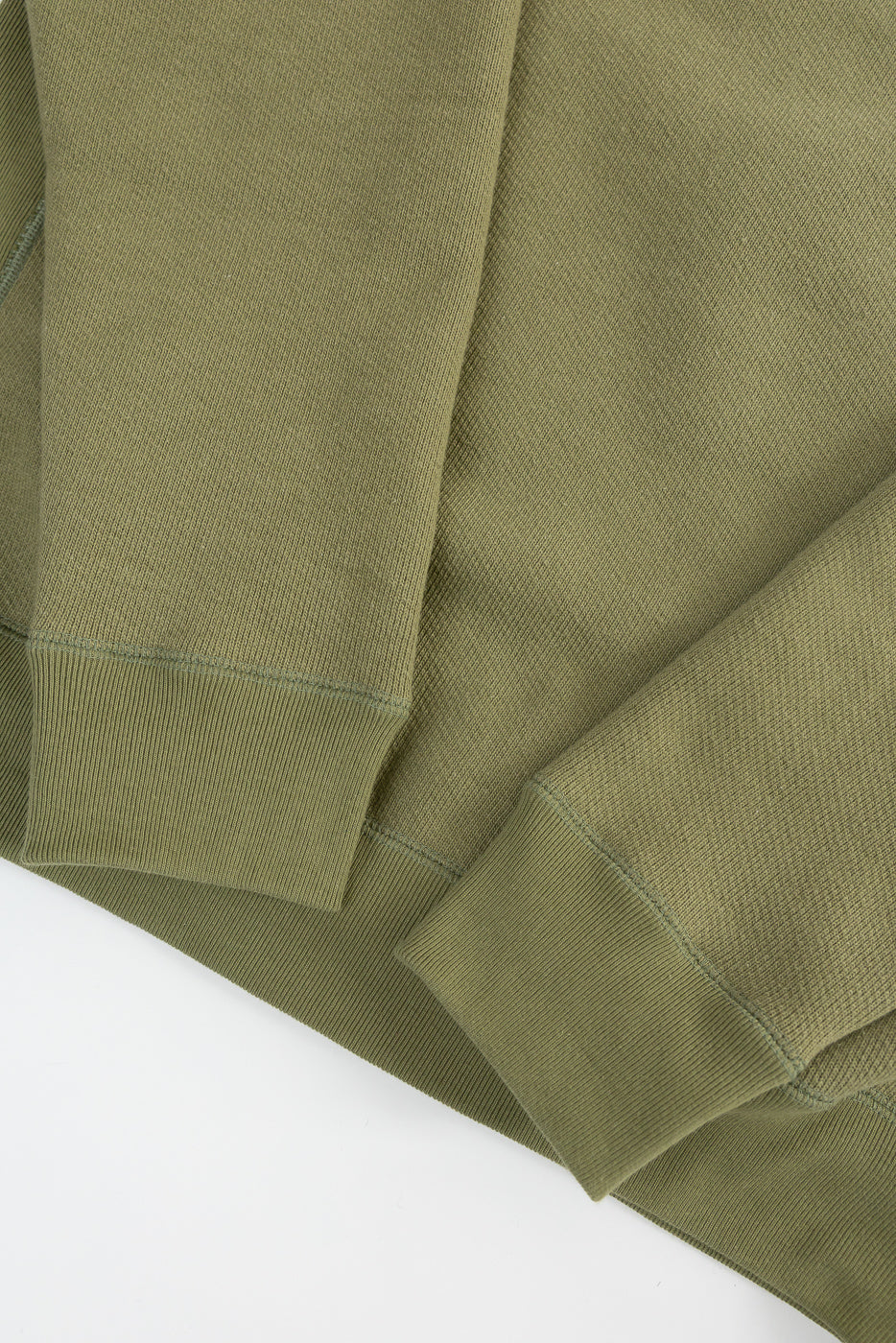 Close-up of sage green French terry pullover crewneck, cuff and hem details, front view