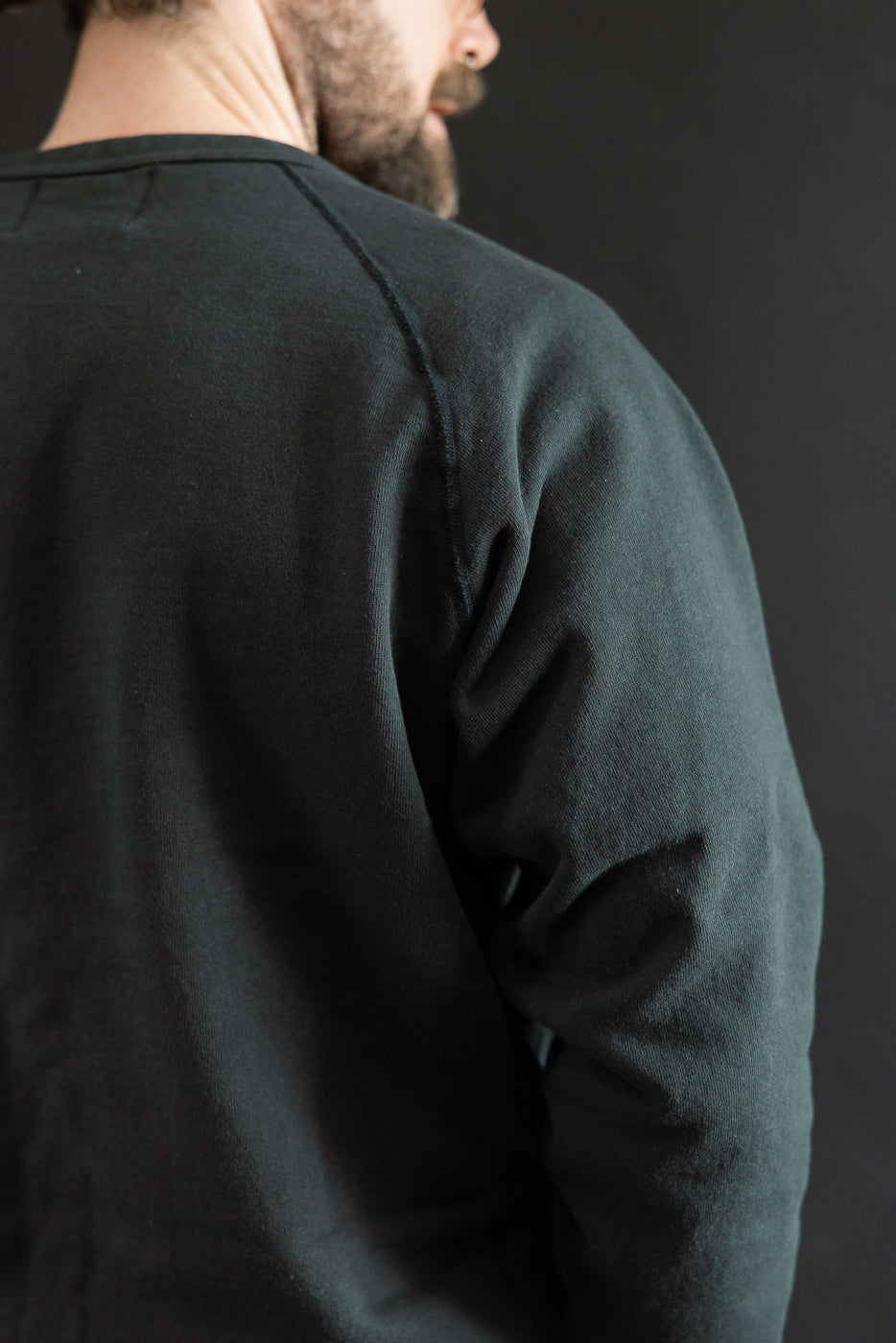 Model wearing Wonder Looper's Pullover Crewneck in Super Looper French Terry. The charcoal shirt showcases a textured surface with raglan sleeves and a ribbed neckline, highlighting its luxurious and unique fabric.