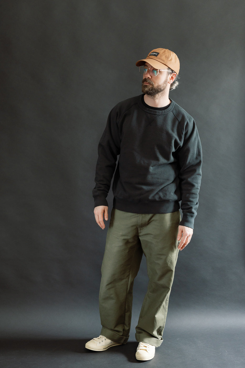 A 5'9 Caucasian male model showcases the Pullover Crewneck - Super Looper French Terry - Sumi, highlighting the textured French terry fabric and modern athletic fit with raglan sleeves and ribbed details.