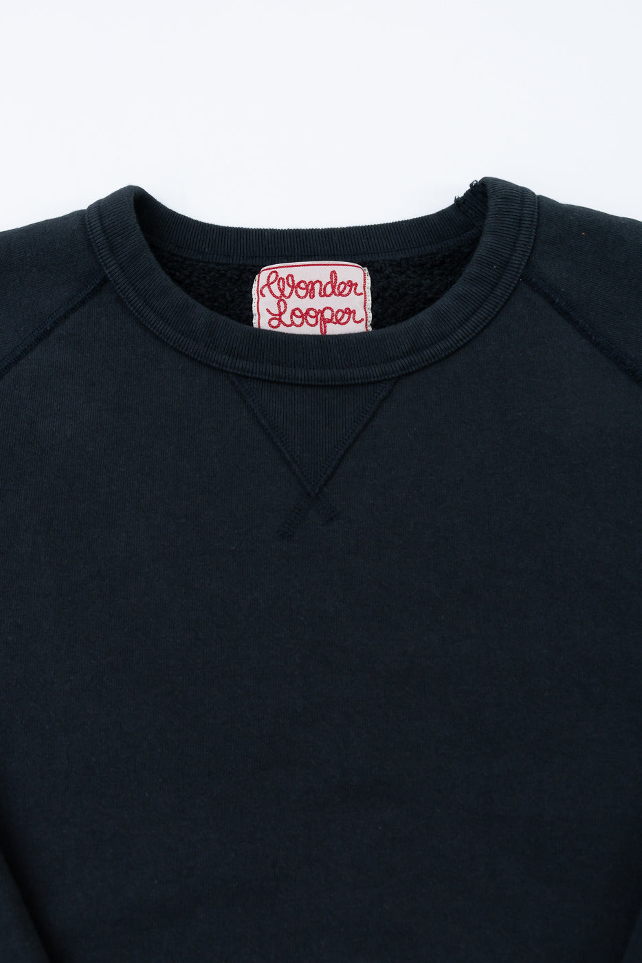 Pullover Crewneck - Super Looper French Terry - Sumi showcases a ribbed neckline with a vintage-style V stitch detail, highlighting its premium craftsmanship and textured finish. Woven tag reads Wonder Looper.