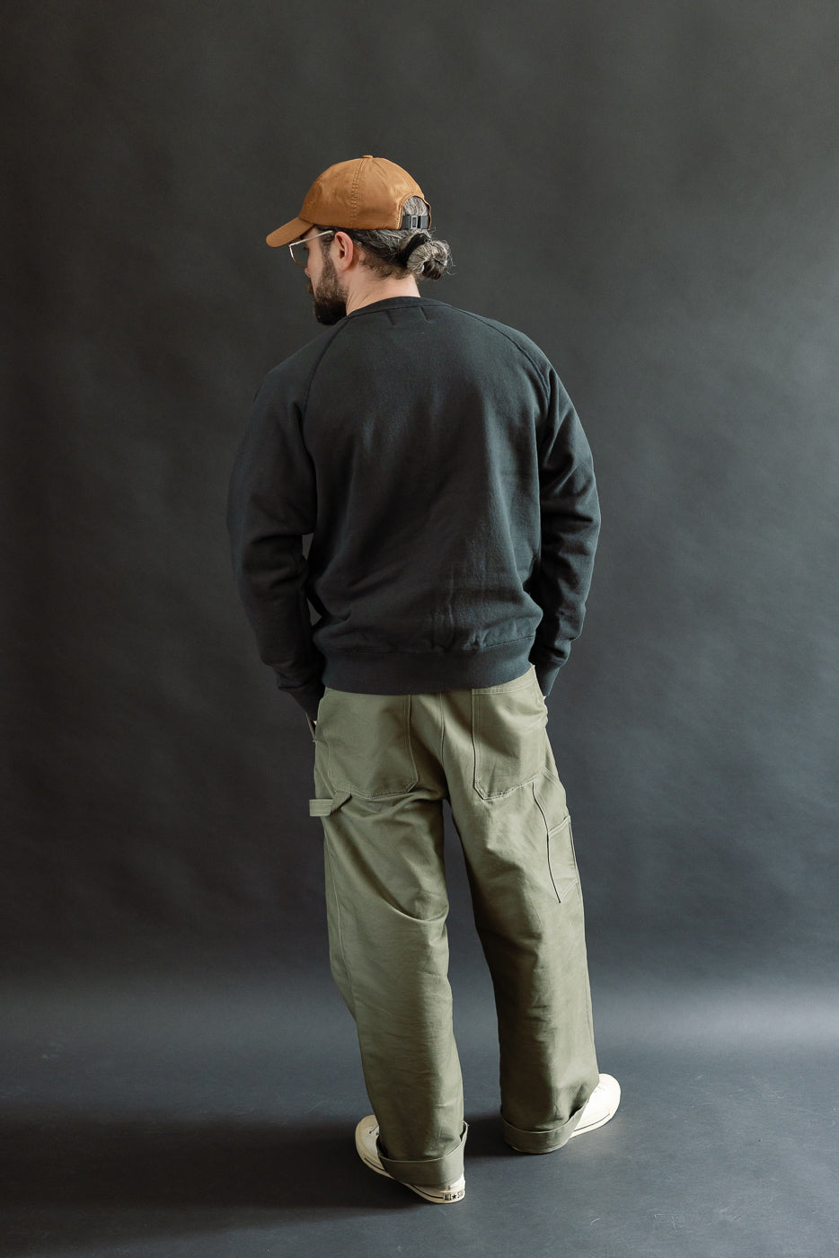 Model wears the Pullover Crewneck - Super Looper French Terry - Sumi, showcasing its unique loopback texture, modern athletic fit, raglan sleeves, and ribbed details against a dark gray backdrop.