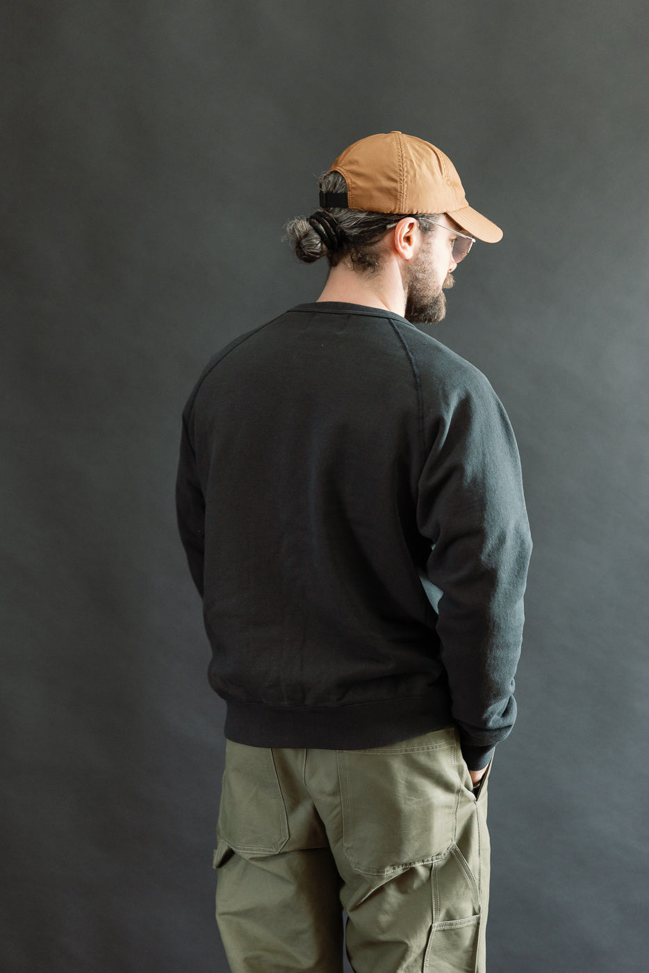 A man wears the Pullover Crewneck - Super Looper French Terry - Sumi, showcasing its textured French terry fabric with raglan sleeves and a V-gusset neckline, embodying Dant's premium menswear aesthetics.