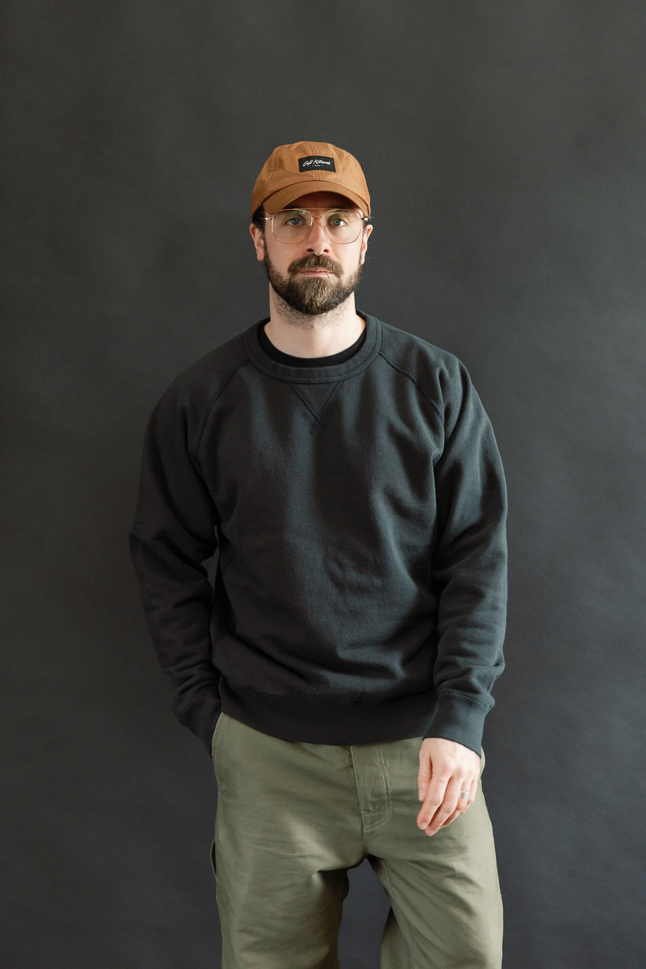 Model wears Pullover Crewneck - Super Looper French Terry - Sumi, showcasing its modern athletic fit with raglan sleeves and ribbed side panels, crafted from textured Tsuriami fabric.