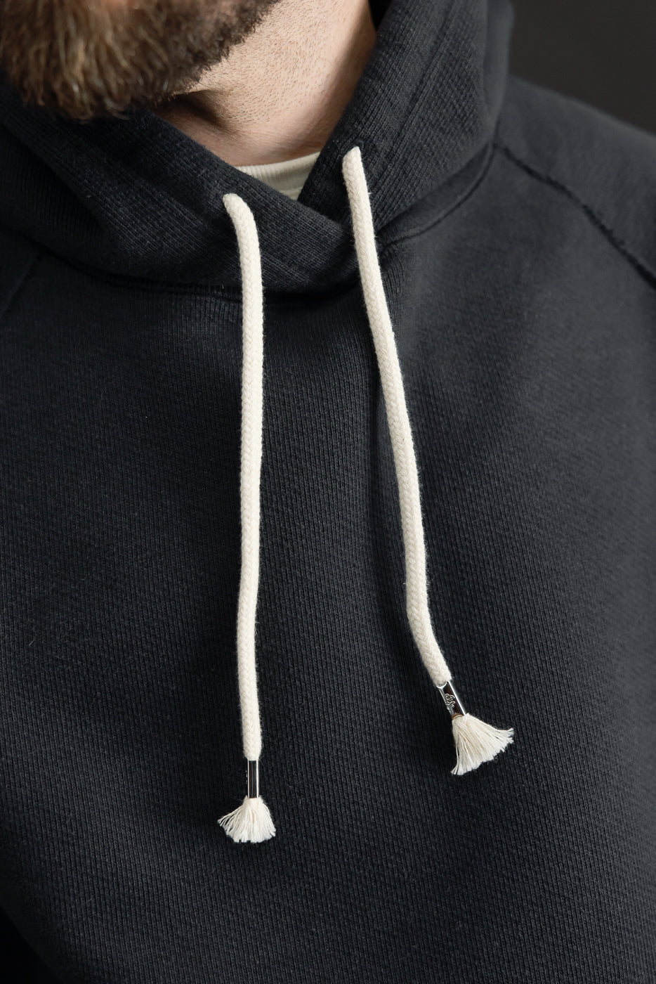 Close-up front view of a black hoodie's drawstring and fabric texture on a male model.