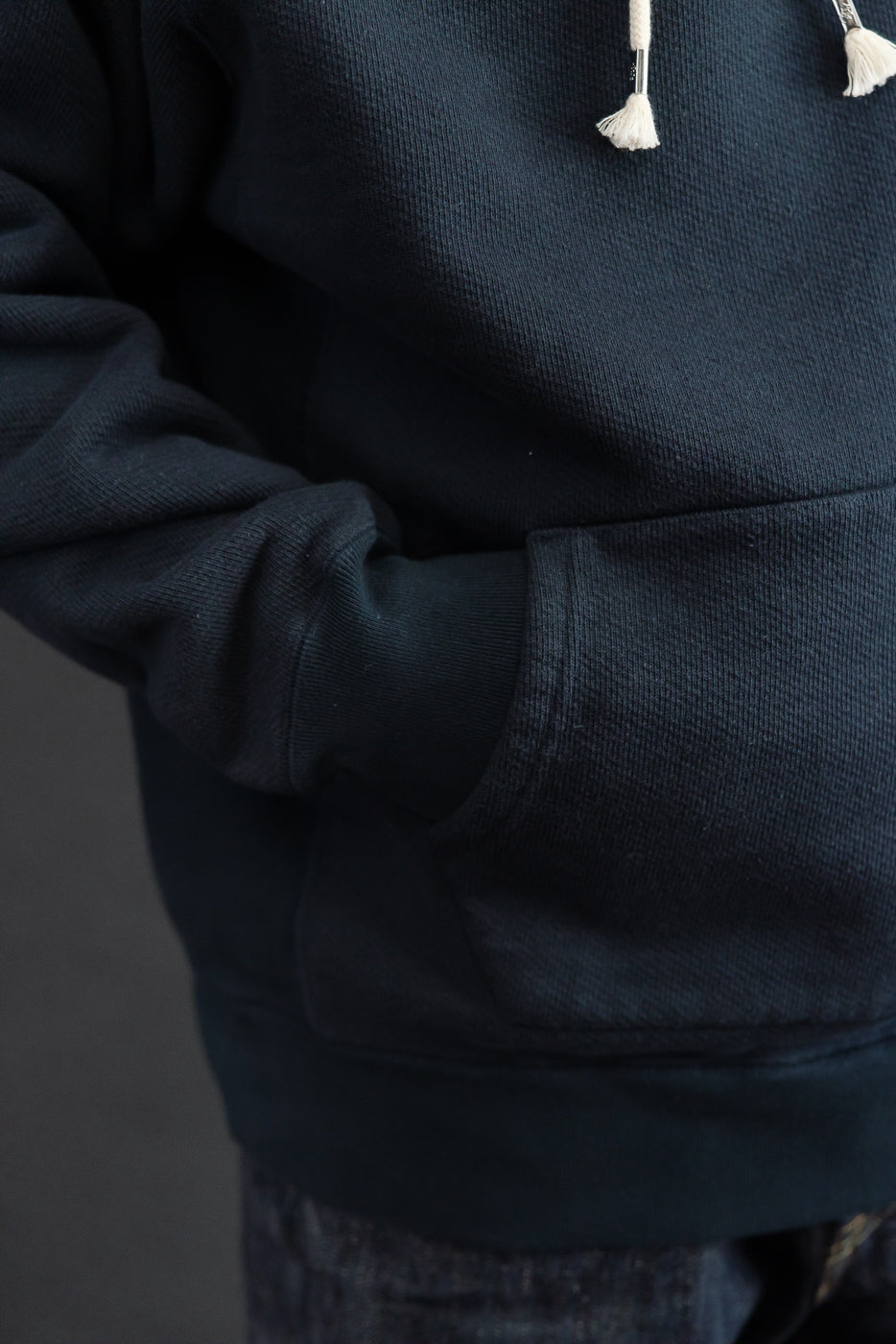 Close-up front view of a navy blue hoodie showing the kangaroo pocket and fabric texture.