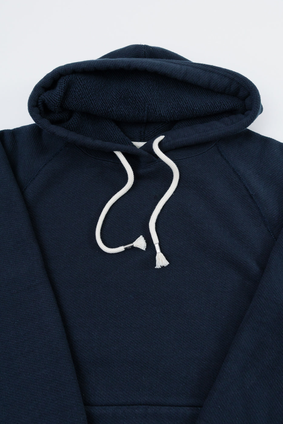 Close-up front view of a navy blue hoodie showing the hood, white drawstrings, and fabric texture.