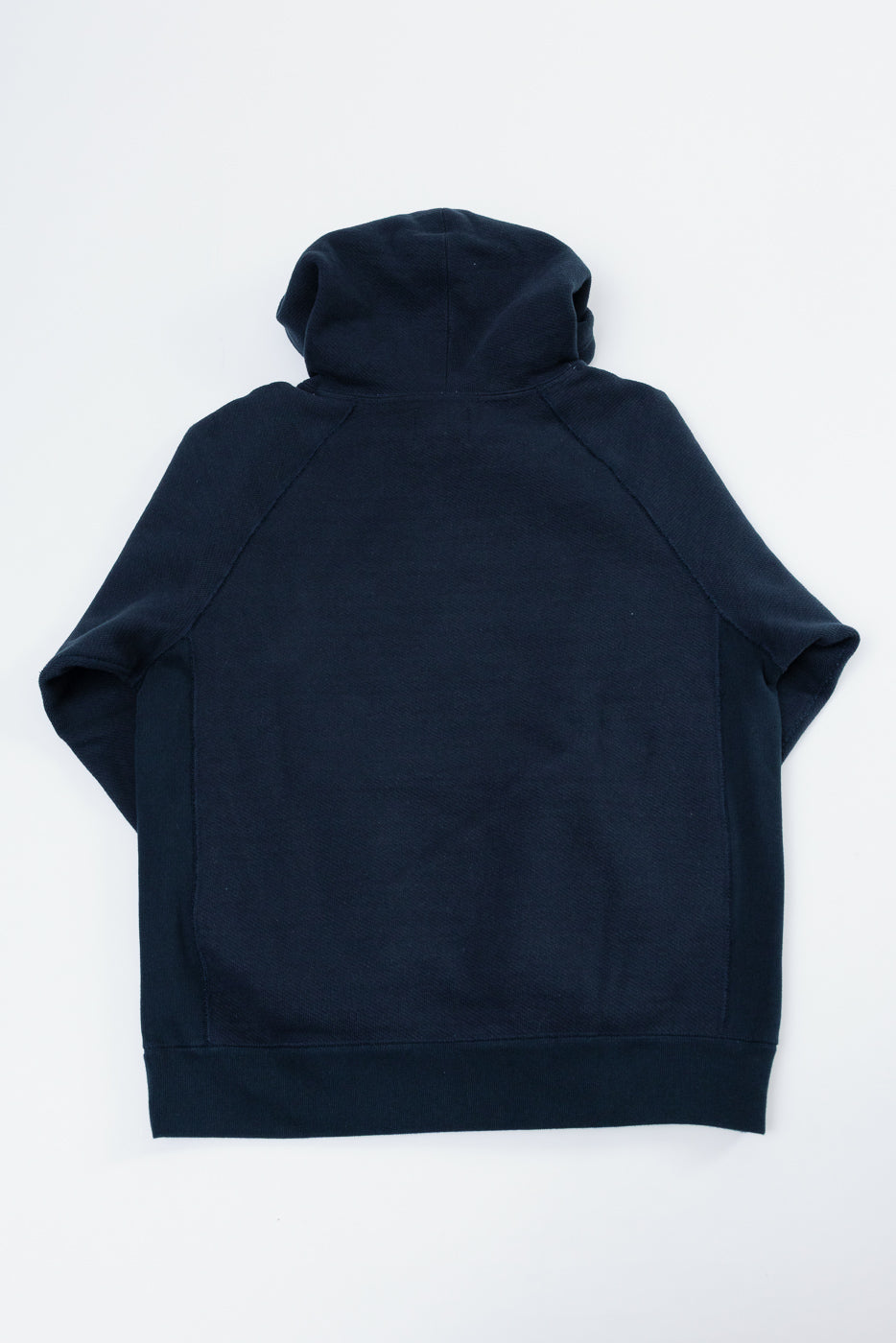 Back view flat lay of a navy blue hooded sweatshirt with raglan sleeves and ribbed hem.
