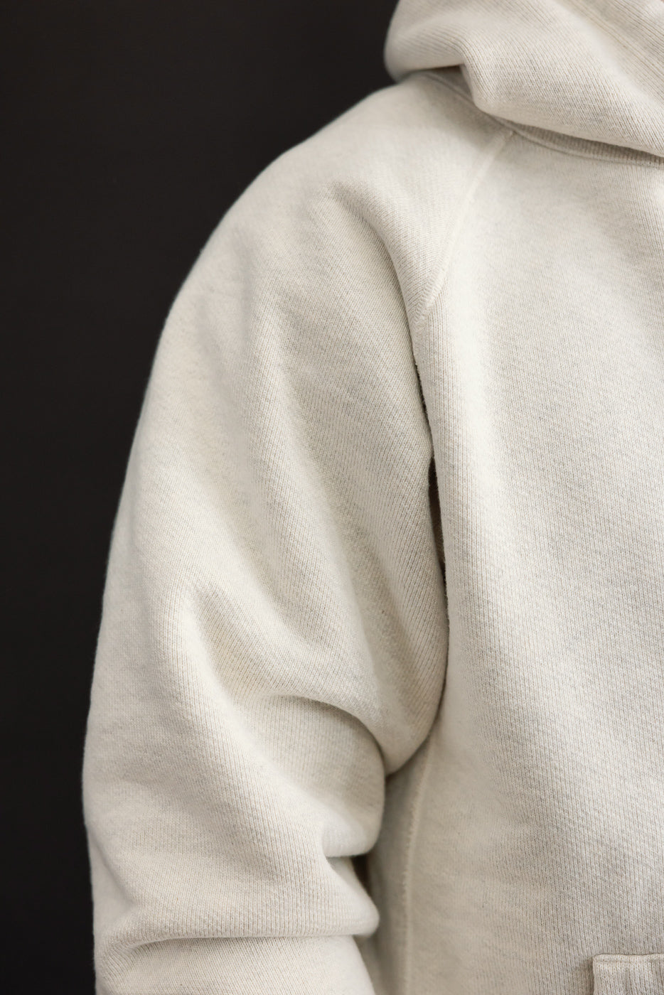 Close-up of the right sleeve and shoulder of a white hoodie on a male model, 5'9