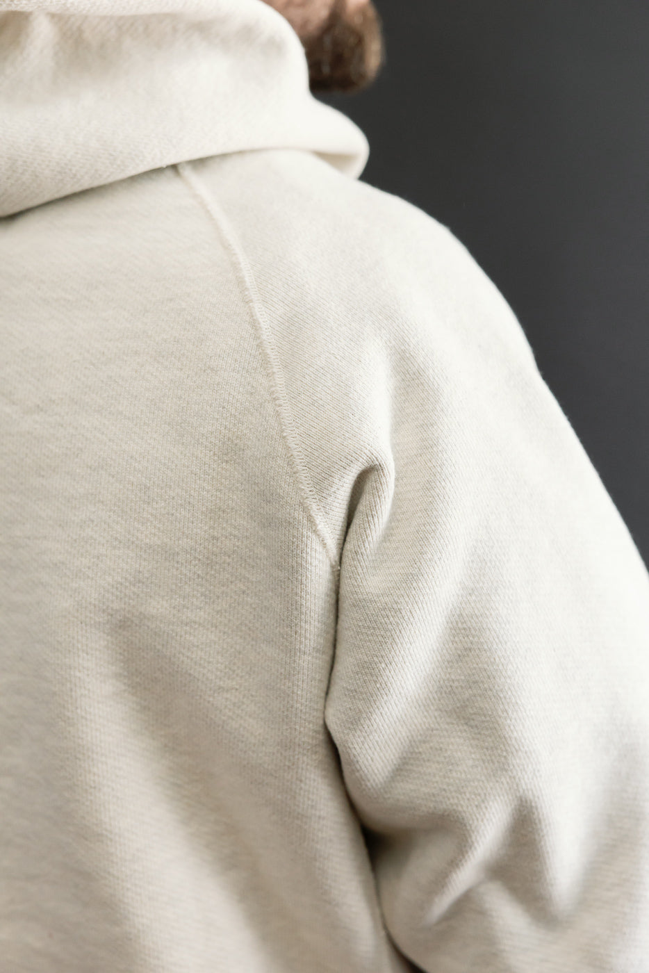Close-up of back shoulder and hood of cream hoodie on male model, 5'9