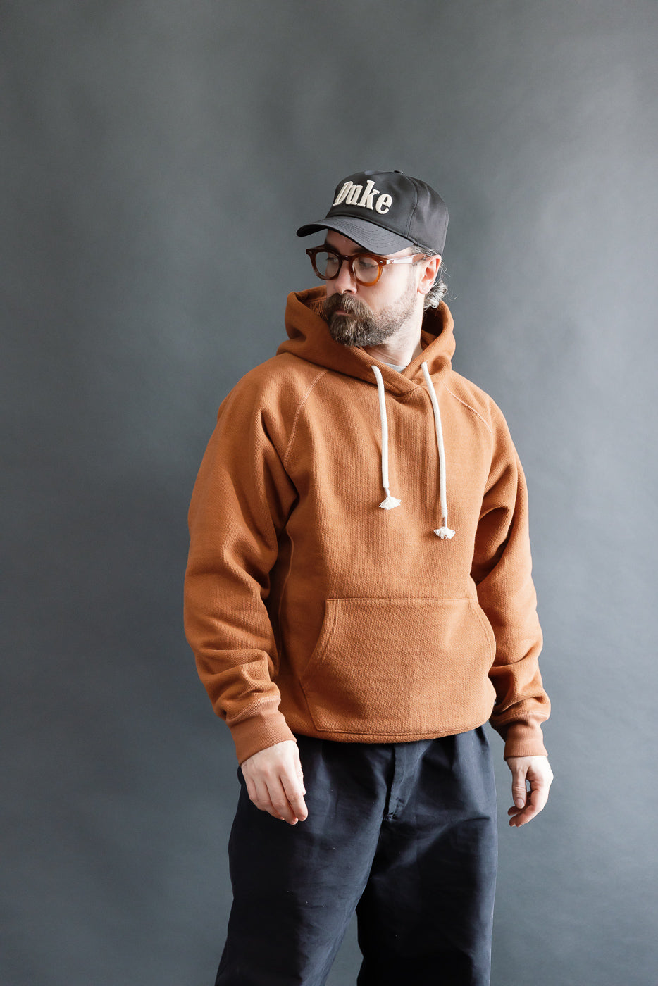 Male model 5'9 165lbs athletic build wearing rust French terry pullover hoodie, front view full body