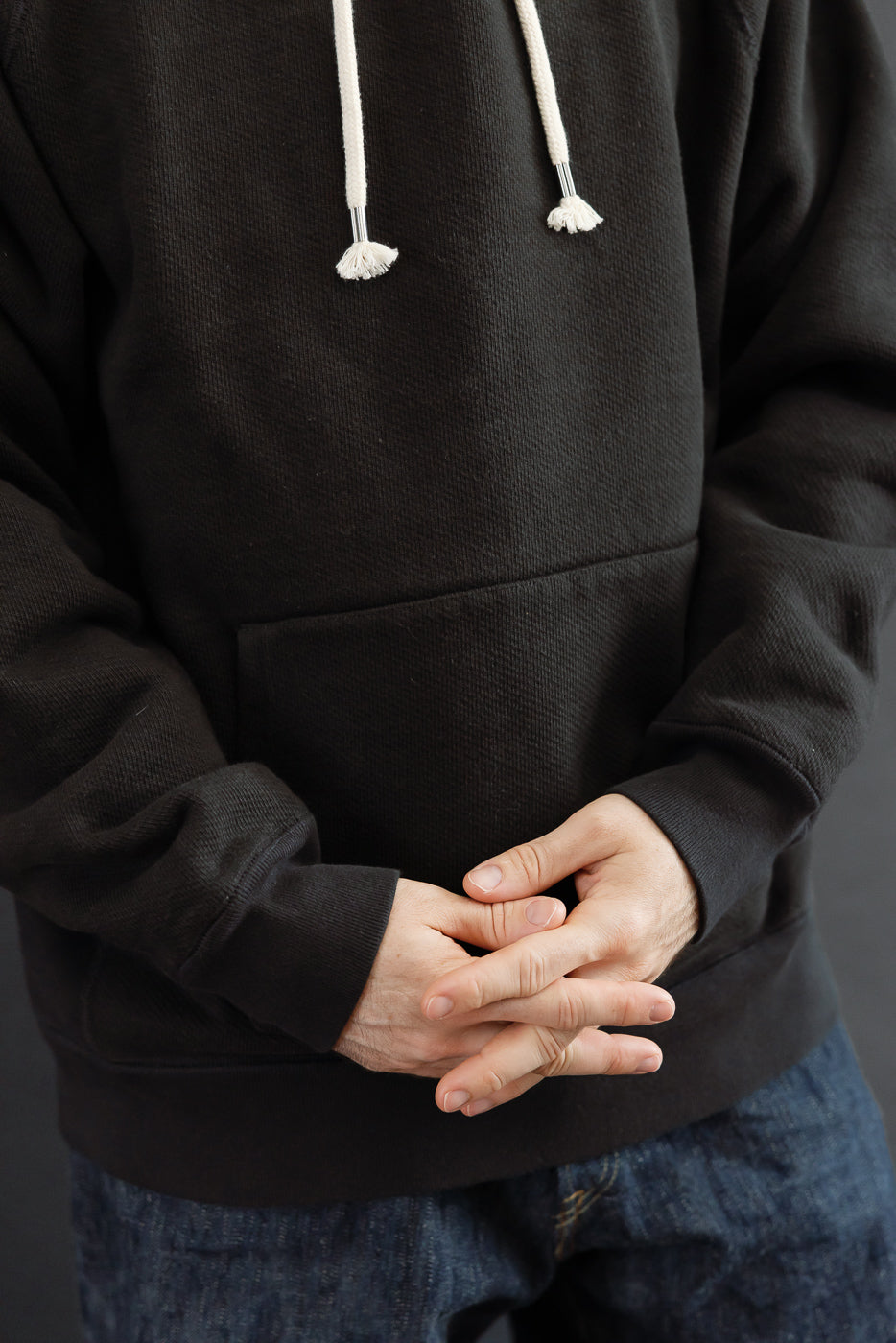 Close-up front view of a black hooded sweatshirt on a 5'9