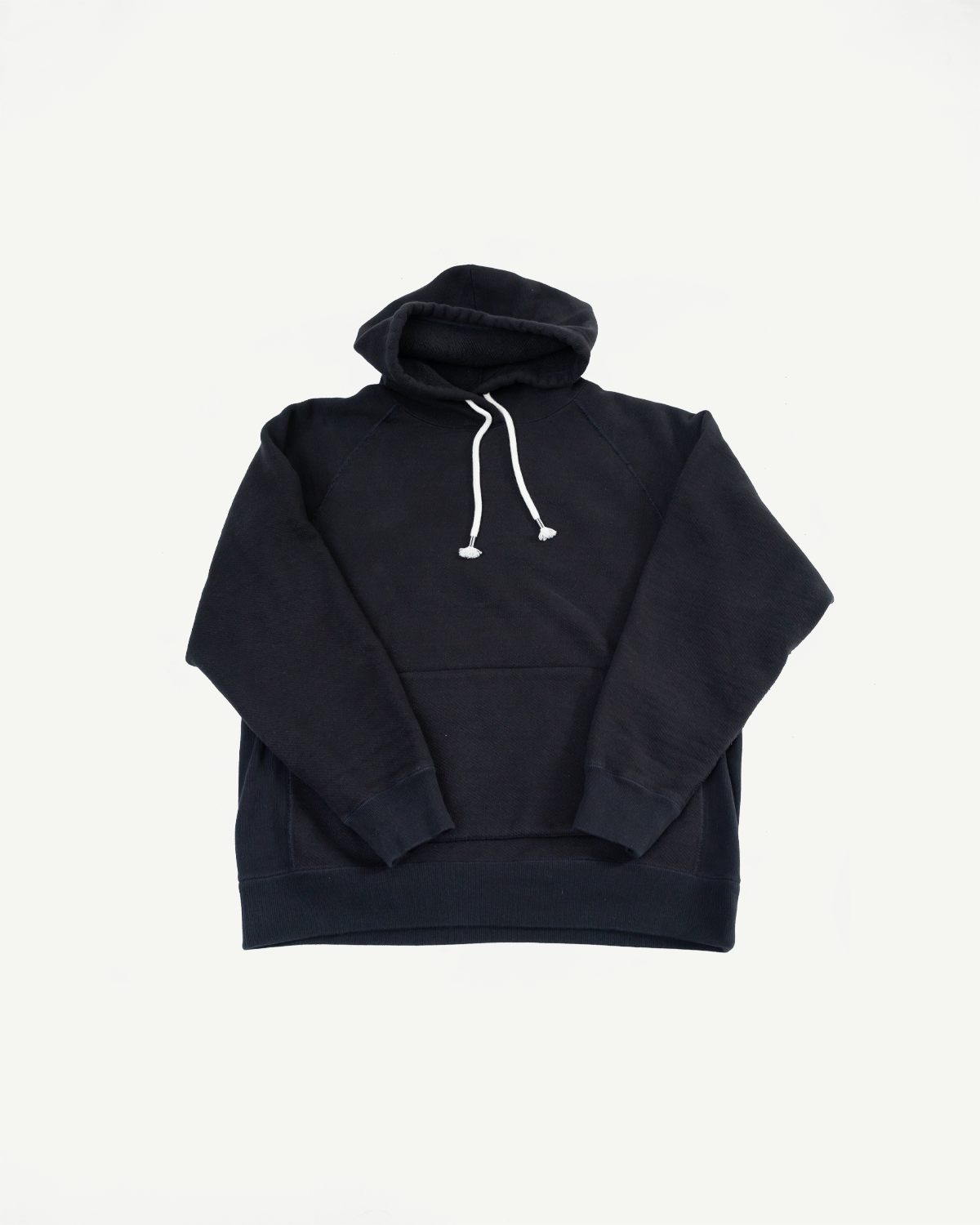 Front view flat lay of a black hooded sweatshirt with white drawstrings and a kangaroo pocket.
