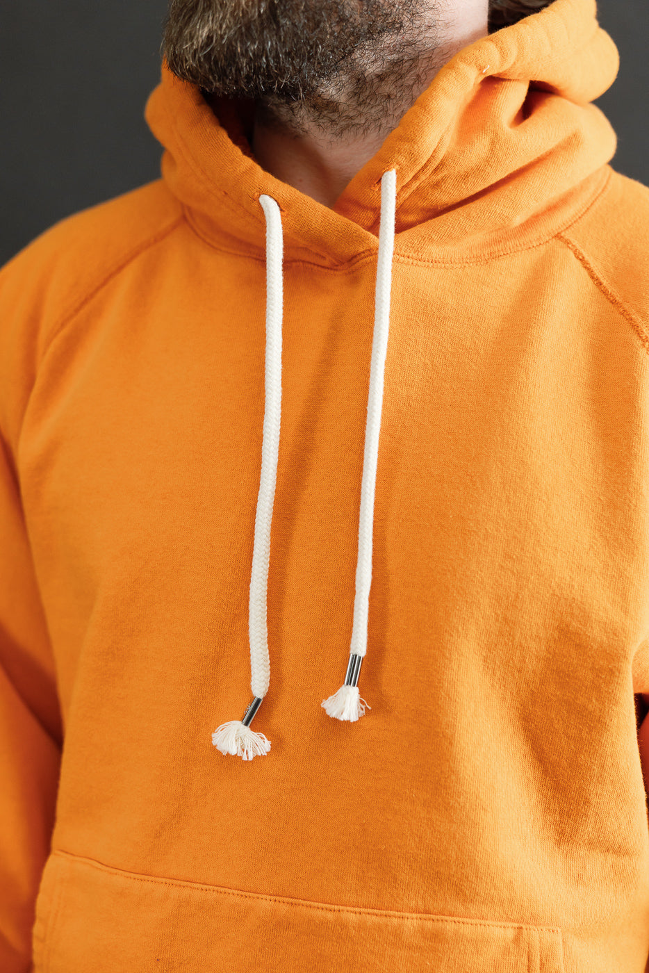 Close-up of the Pullover Hoodie - Super Looper French Terry - Orange, highlighting its textured loopback interior and smooth exterior with white drawstrings, showcasing Dant's focus on premium, heritage-inspired apparel.