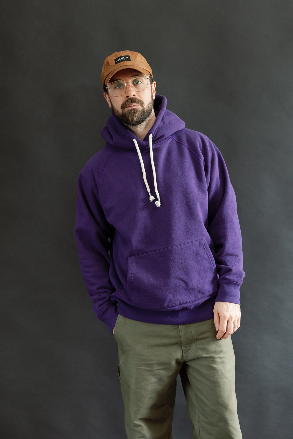 Man wearing Pullover Hoodie - Super Looper French Terry - Purple, showcasing its smooth exterior and athletic fit, with raglan sleeves and a drawstring hood, embodying Dant's premium menswear style.