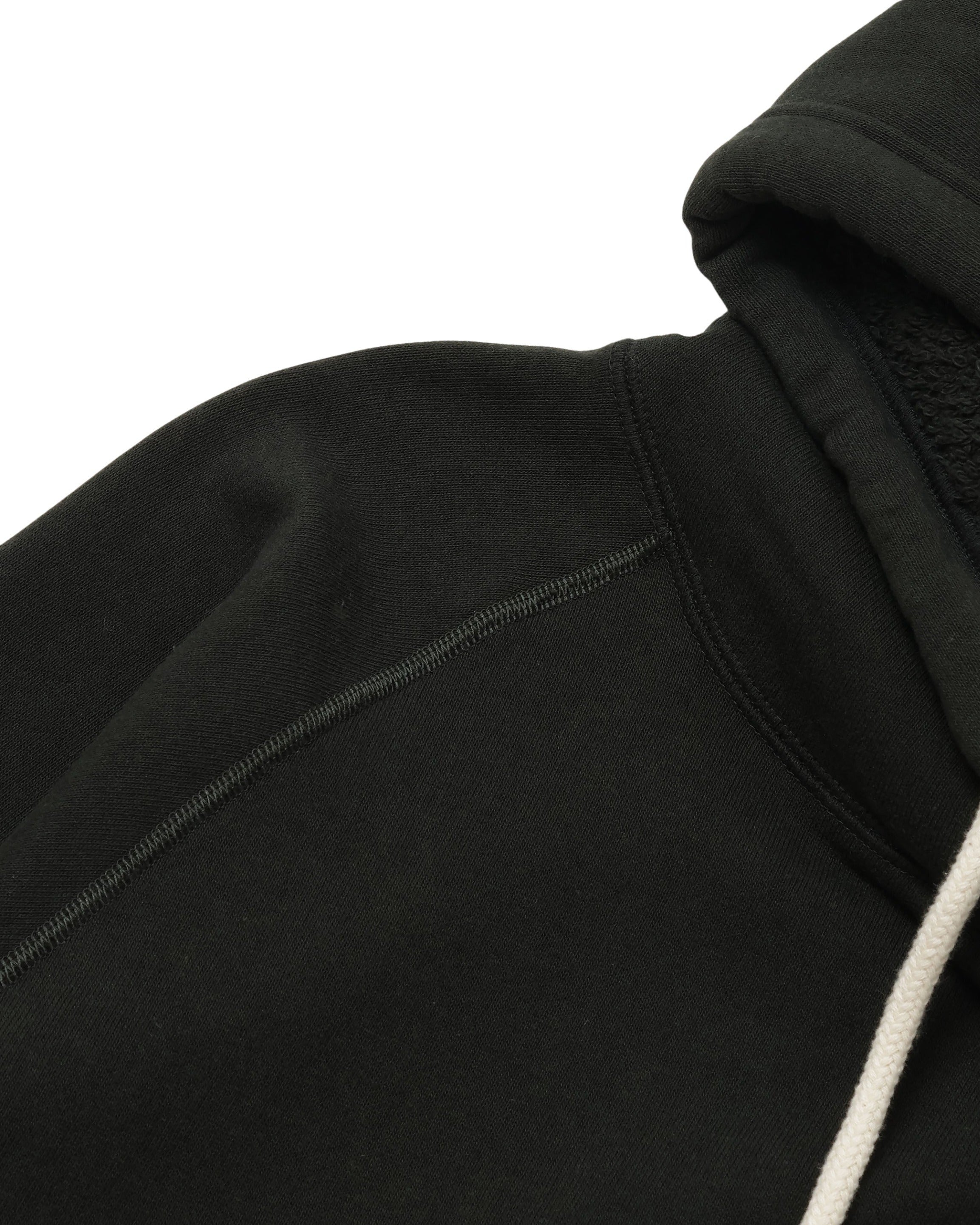 Close-up of black French terry pullover hoodie, front left shoulder and hood detail
