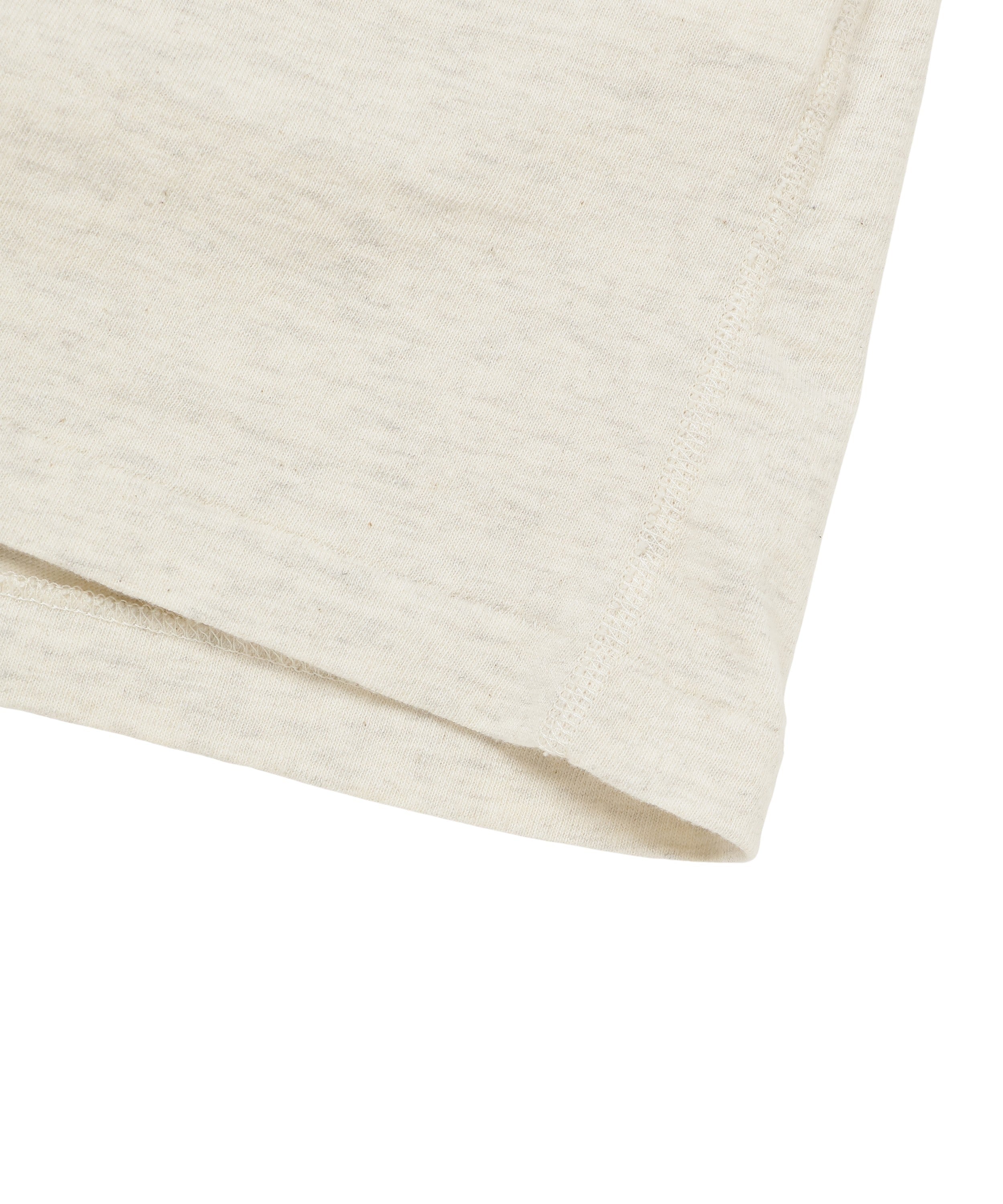 Close-up of recycled cotton t-shirt hem, front lower corner, sand color, fabric texture detail.