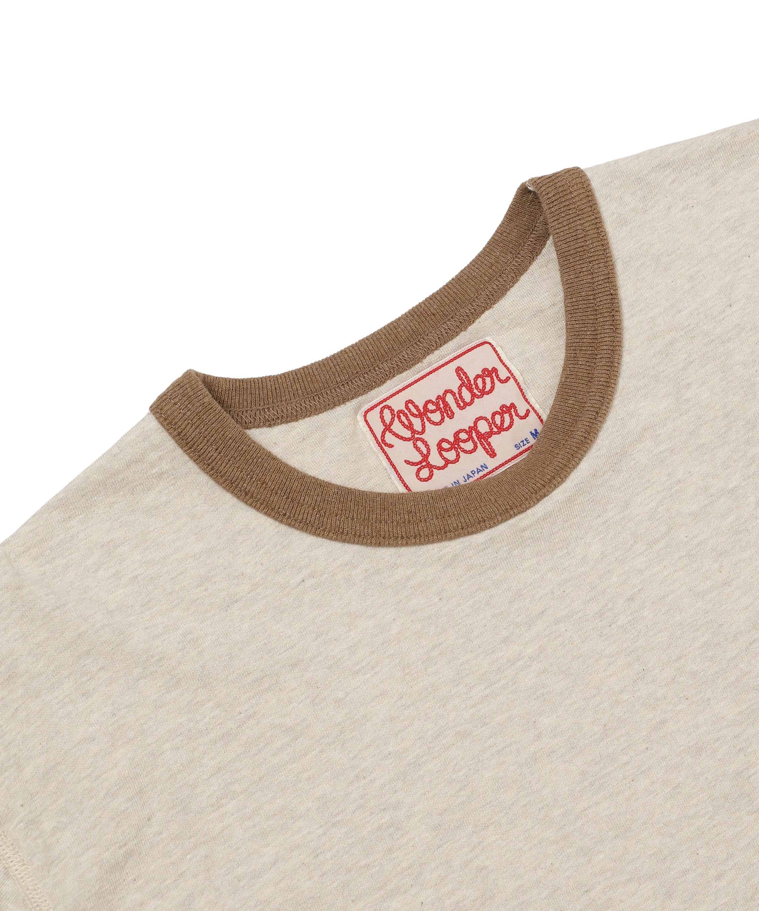 Close-up of front neckline on stone recycled cotton ringer tee, brown ribbed collar, visible neck tag.