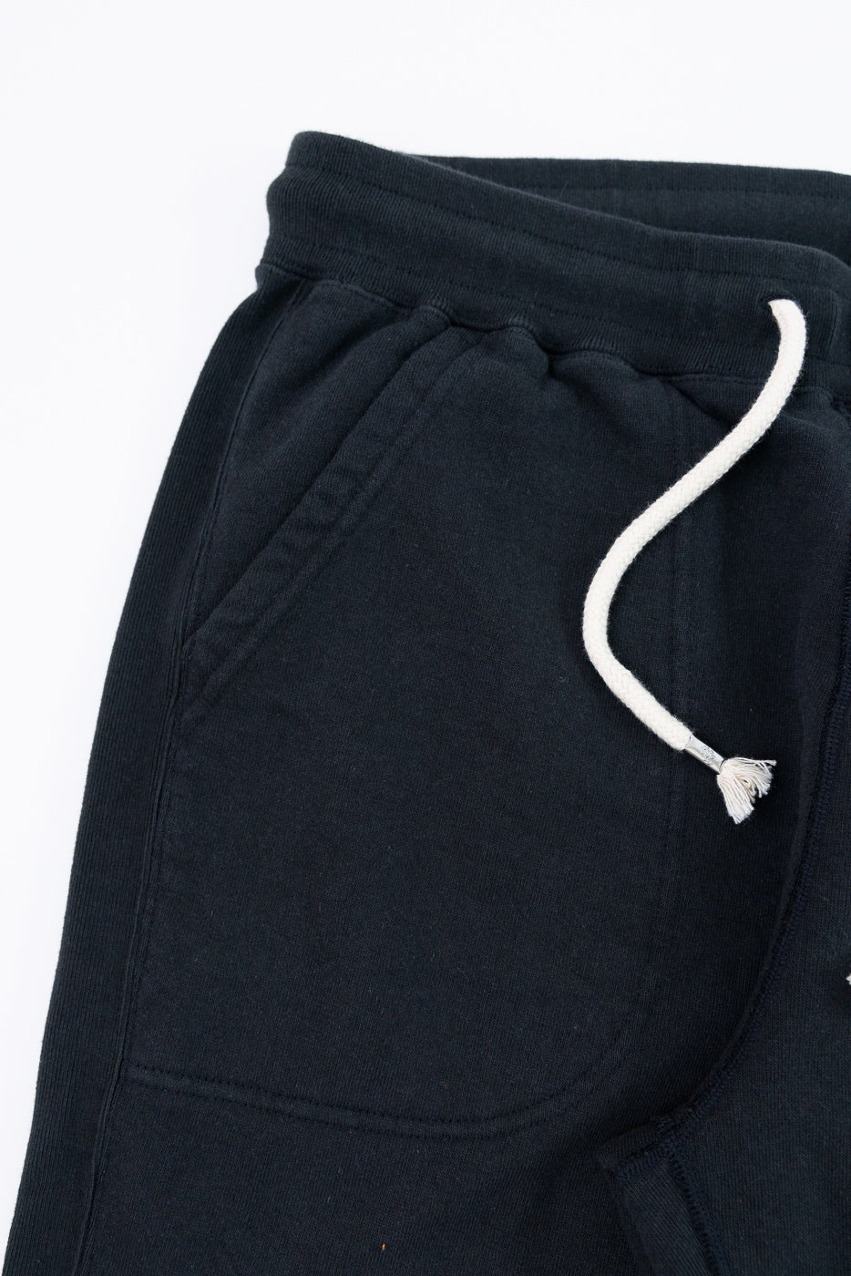 Close-up of black joggers' front waistband with white drawstring and pocket detail