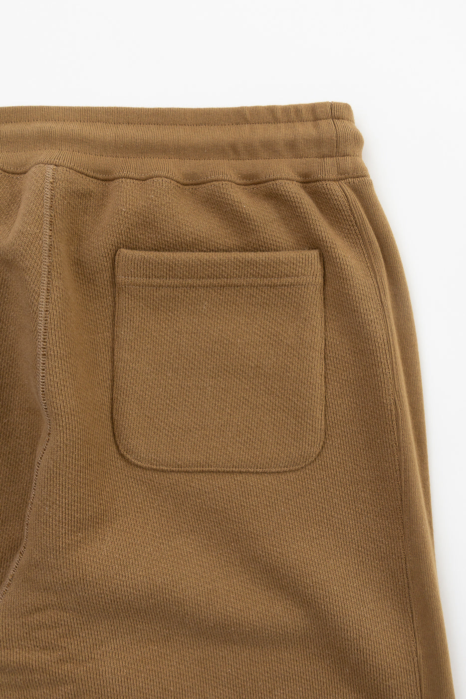 Close-up of Wonder Looper sweatpant back pocket, showing dune French terry fabric texture