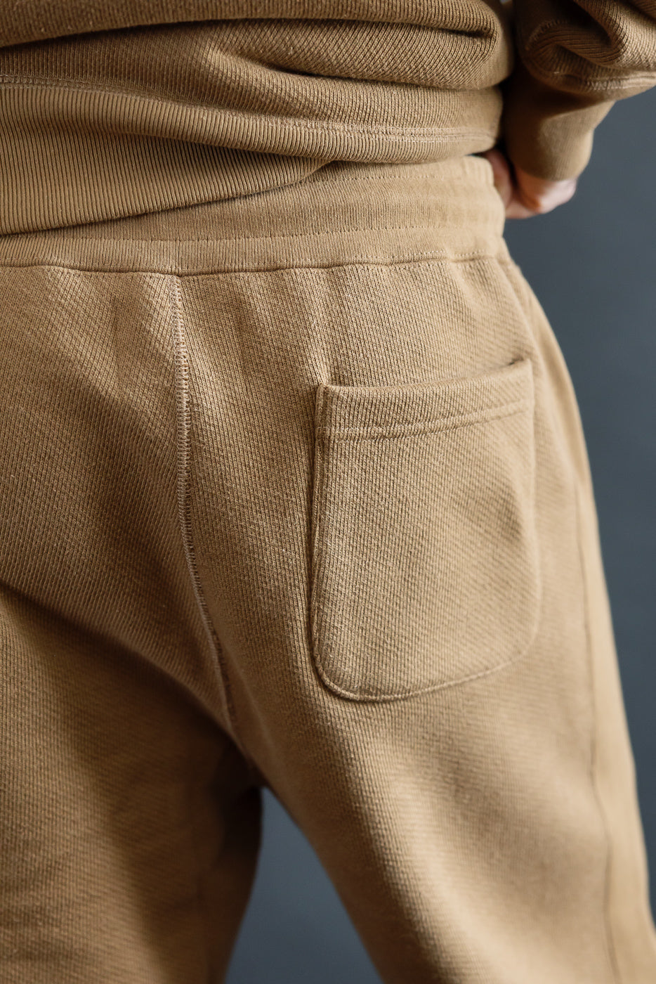 Close-up of back pocket and waistband on Wonder Looper Dune sweatpants, male model, rear view