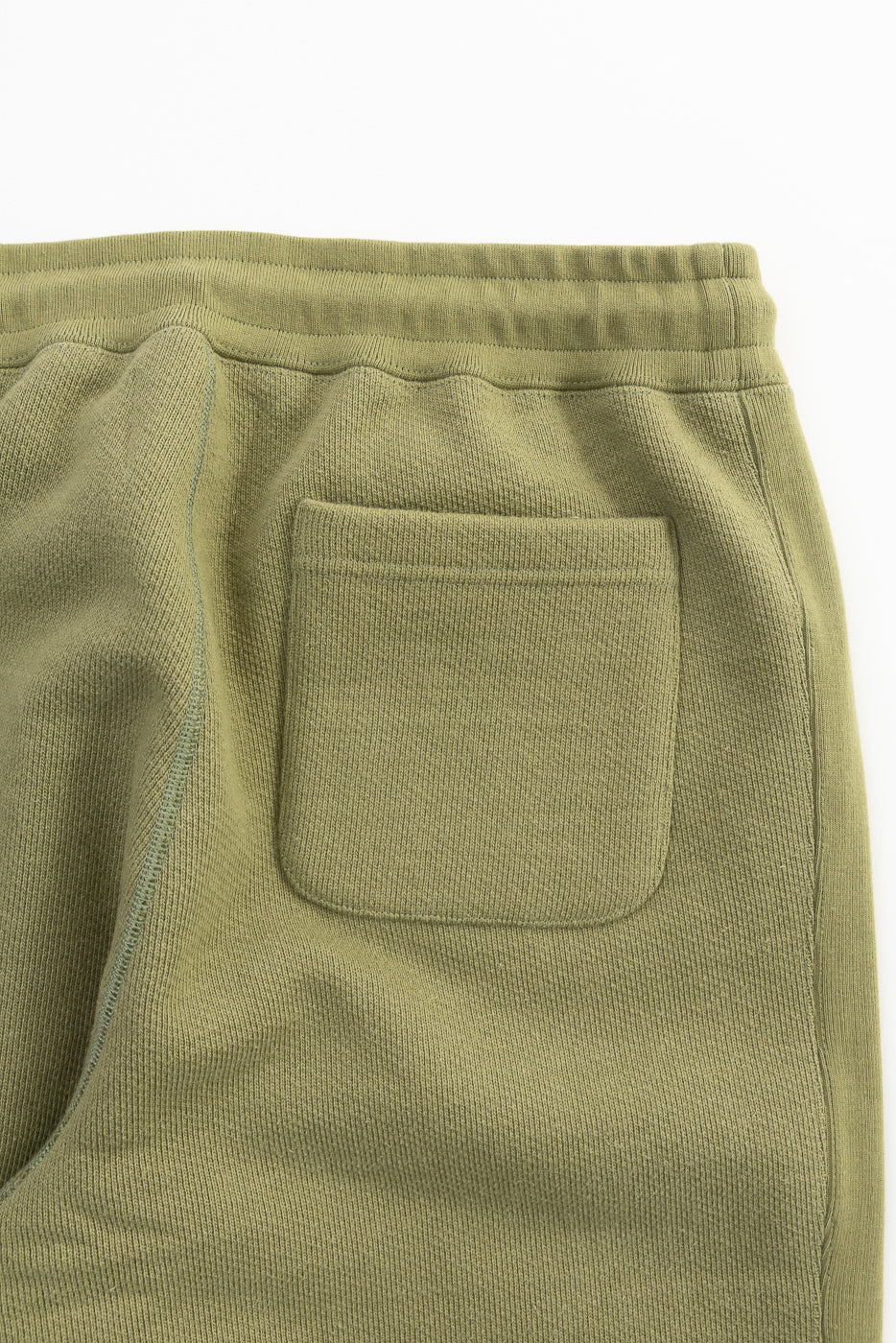 Close-up of back pocket and waistband on sage French terry sweatpant, rear view.