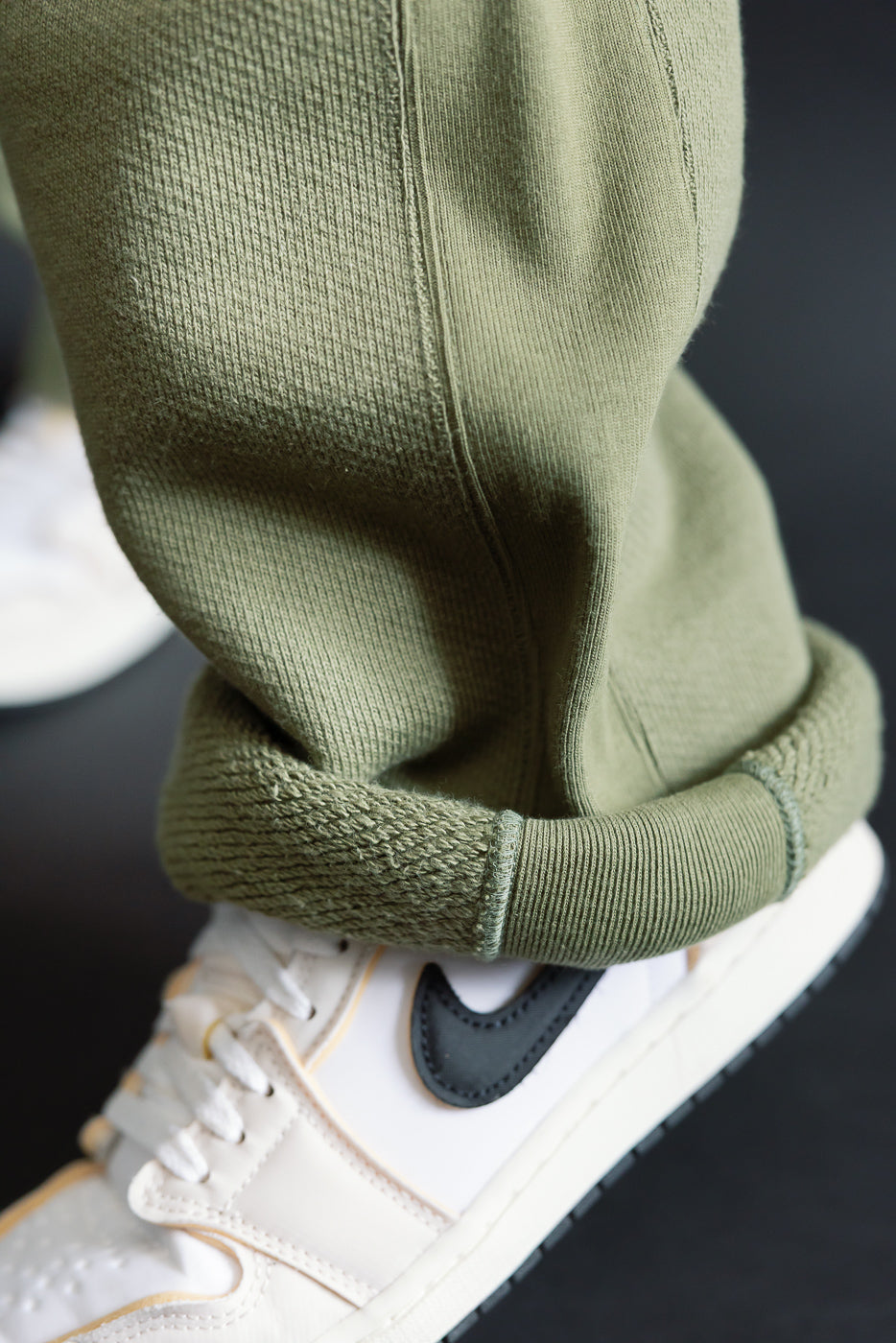 Close-up of sage Wonder Looper sweatpant cuff texture on male model, side view