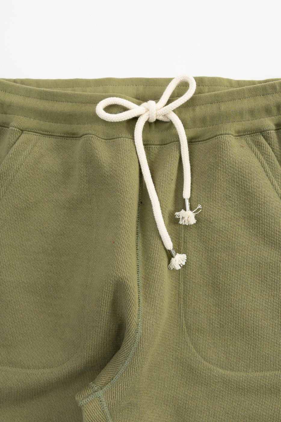 Close-up of sage green Wonder Looper sweatpant front waistband, drawstring, and pocket.