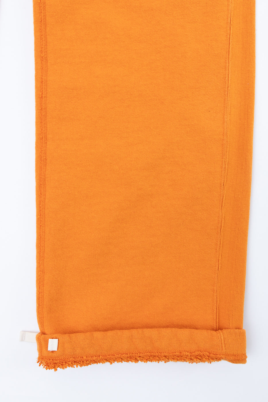 Orange knit scarf flat lay, front view, frayed hem, tag detail