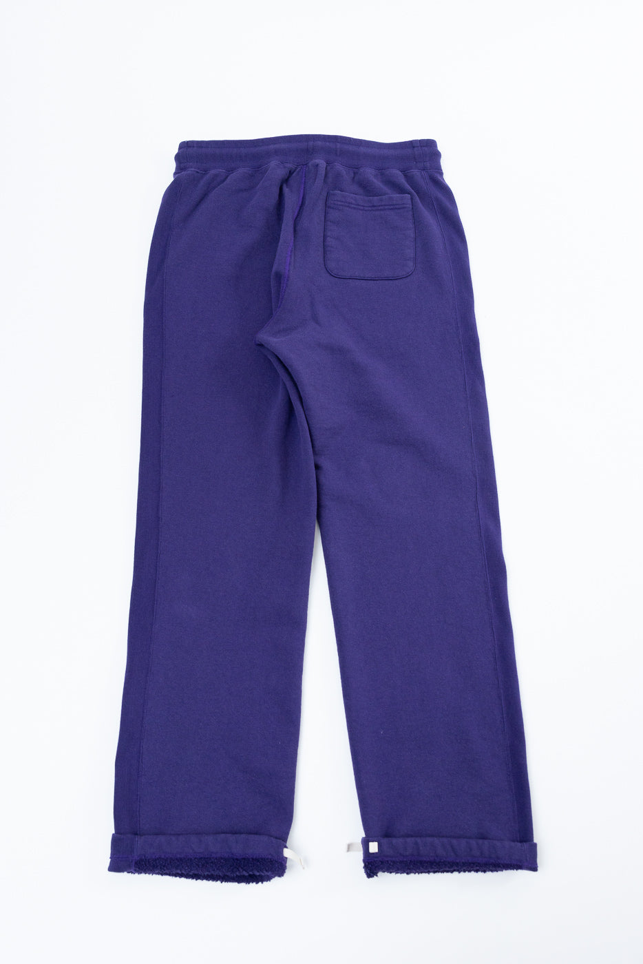 Back view flat lay of purple sweatpants with cuffed hems, drawstring waist, and rear pocket
