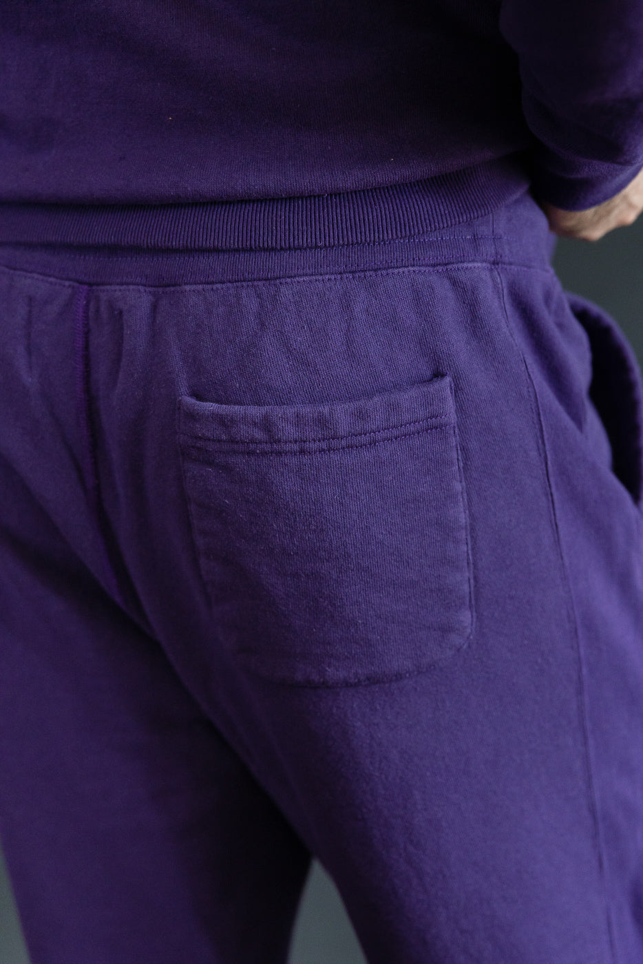 Close-up back view of purple joggers with rear pocket, worn by male model, 5'9