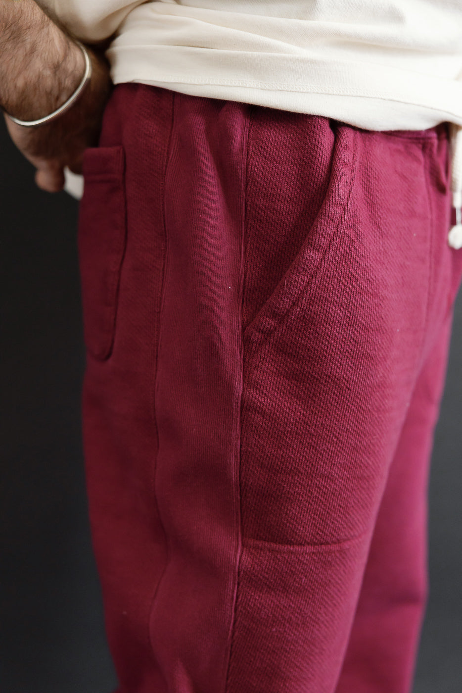 Close-up of the right side of burgundy textured pants on a male model, 5'9