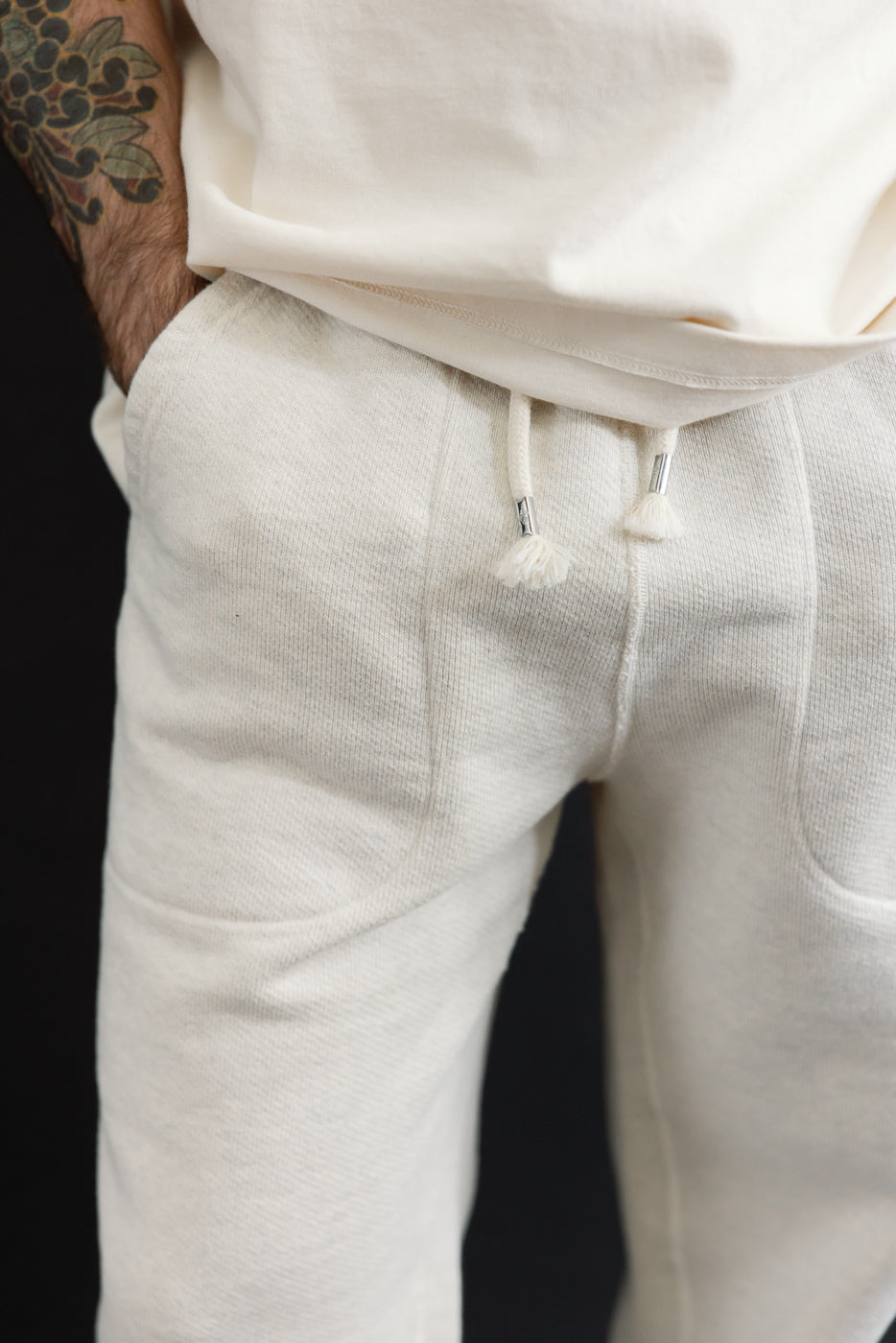 Close-up front view of cream sweatpants on a male model, 5'9