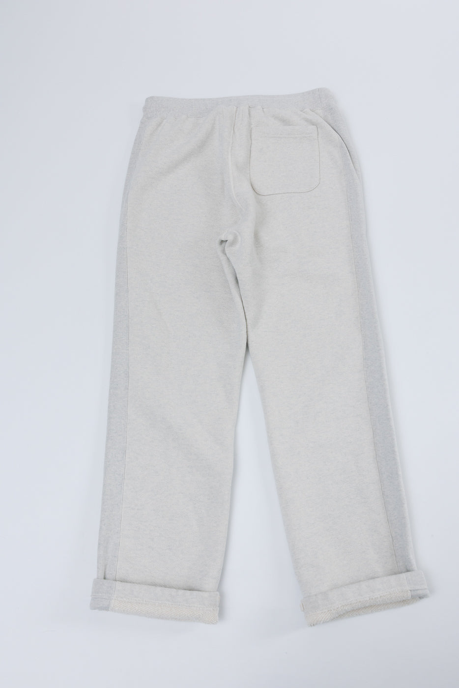 Back view flat lay of light grey sweatpants featuring a rear patch pocket and cuffed hems.