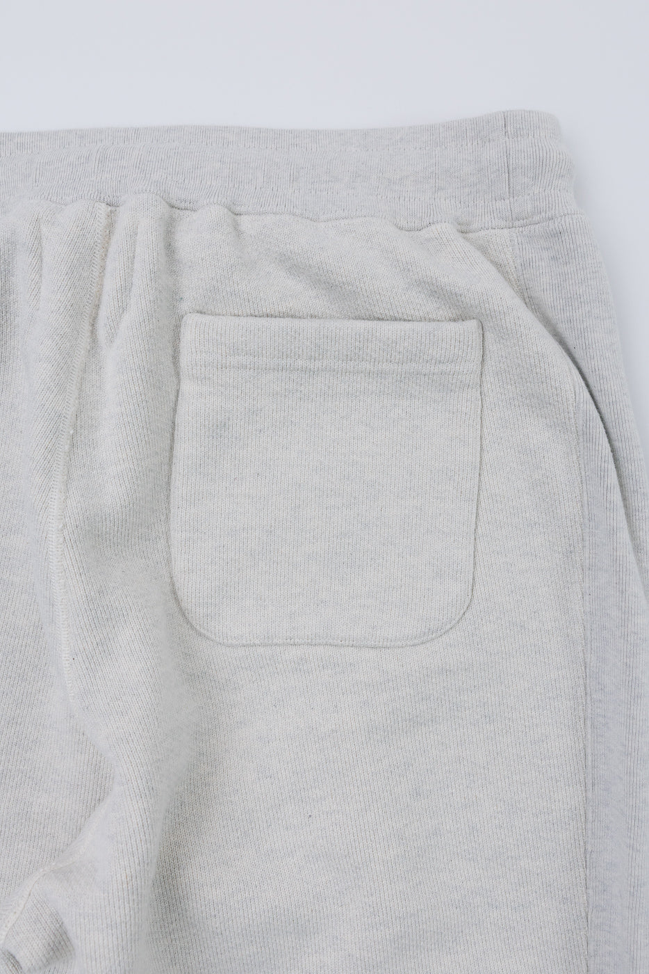 Close-up of the back pocket and waistband on light grey heathered sweatpants.