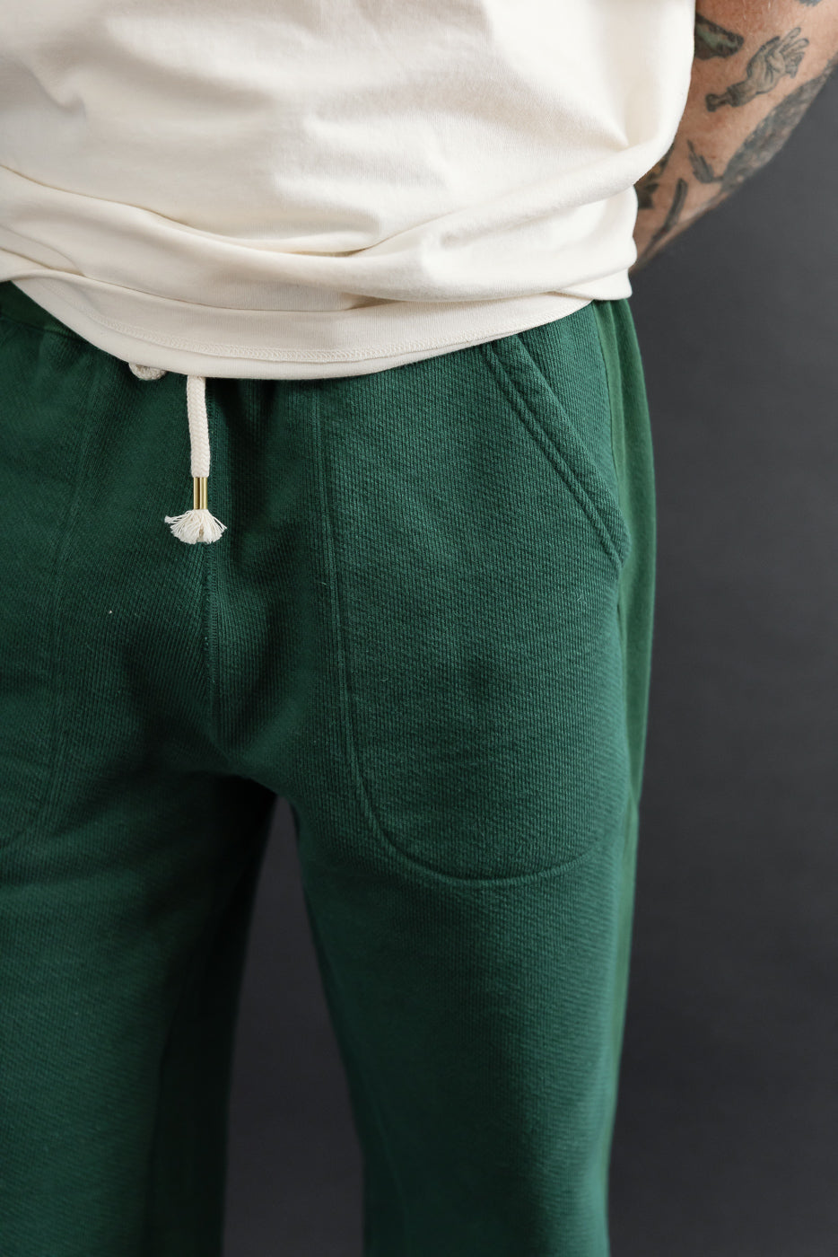 Close-up back view of male model in green sweatpants showing drawstring and fabric texture.