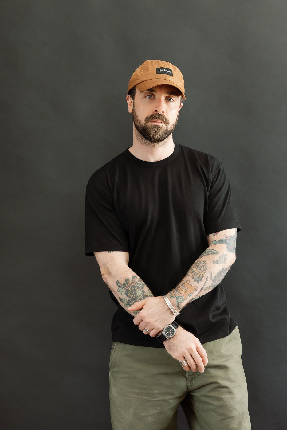 Man models the Ultimate Pima Tsuriami Crewneck T-Shirt - Black, showcasing its relaxed fit and smooth texture. He wears olive-green pants, highlighting the shirt's versatility and premium craftsmanship.