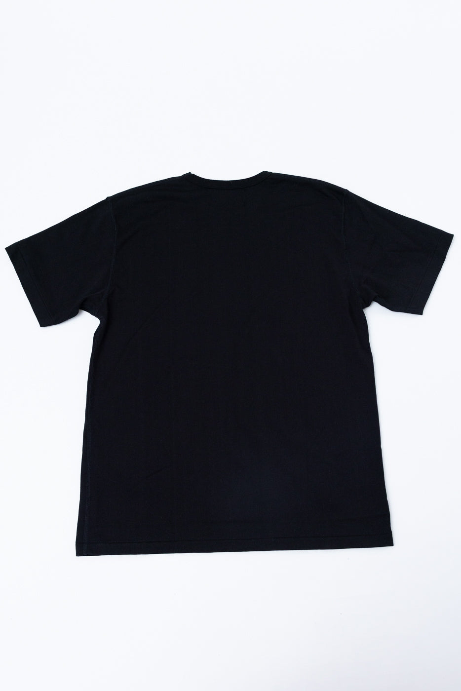 Flat lay of the back of a plain black short-sleeve t-shirt.