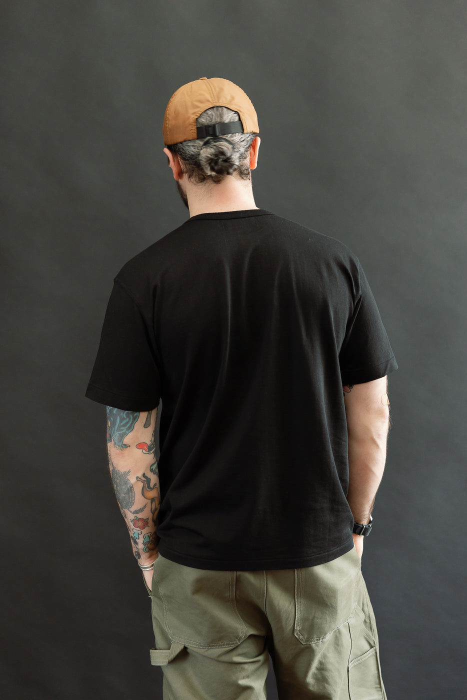 A man models the Ultimate Pima Tsuriami Crewneck T-Shirt - Black, highlighting its smooth, lightweight fabric and athletic fit, with tattoos visible on his arms.