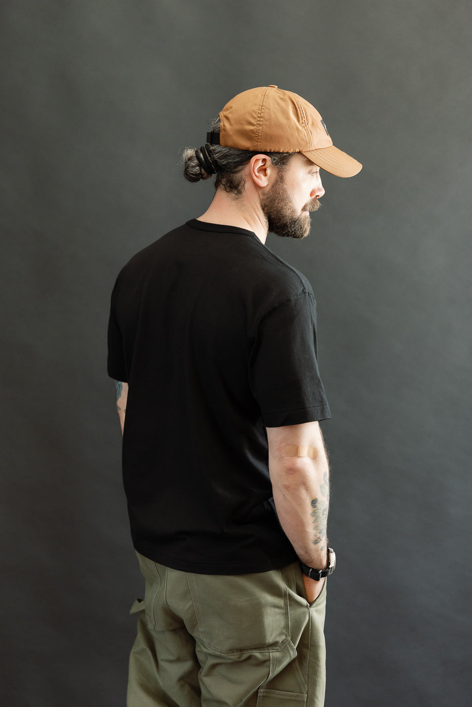 Man in three-quarter profile wearing Ultimate Pima Tsuriami Crewneck T-Shirt - Black, showcasing smooth texture and athletic fit. Features include ribbed collar, flat side seams, and premium Pima cotton fabric.