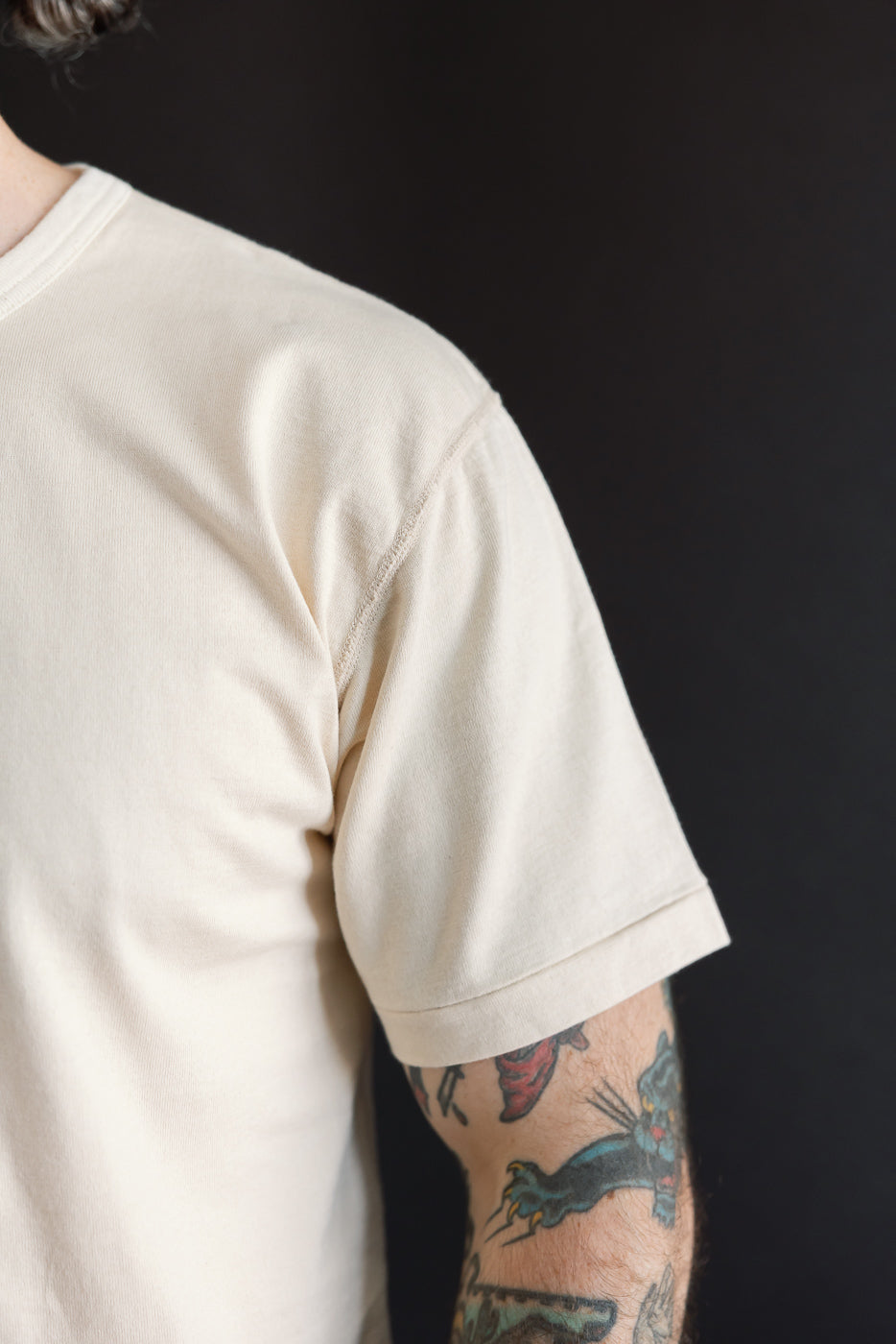 Close-up side view of a cream cotton t-shirt sleeve on a 5'9