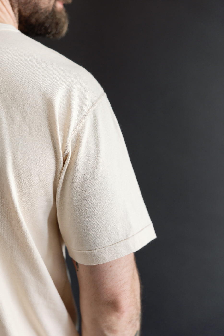 Close-up side view of a cream t-shirt sleeve on a 5'9