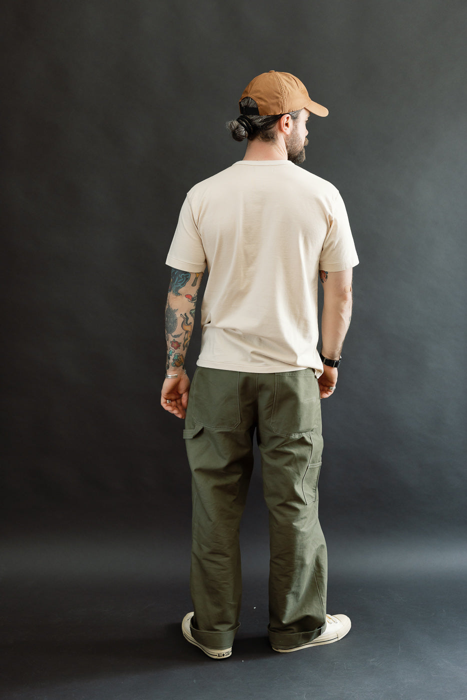 A man models the Ultimate Pima Tsuriami Crewneck T-Shirt - Ecru, highlighting its smooth texture and light fit, paired with olive cargo pants and sneakers, reflecting Dant's premium menswear aesthetic.