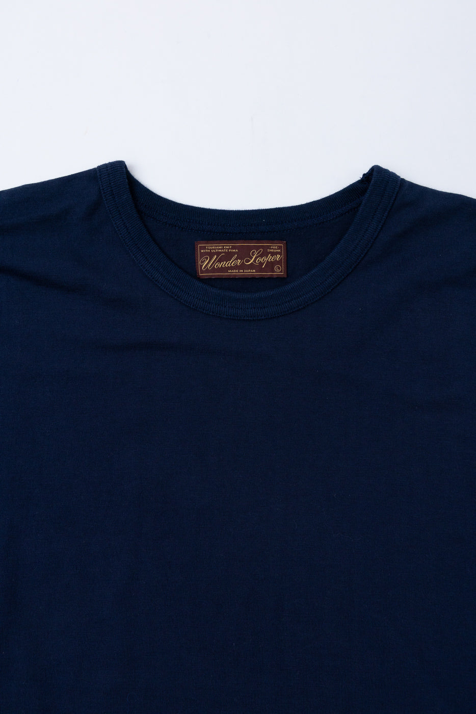 Close-up of the front neck area of a navy t-shirt featuring the Wonder Looper brand tag.