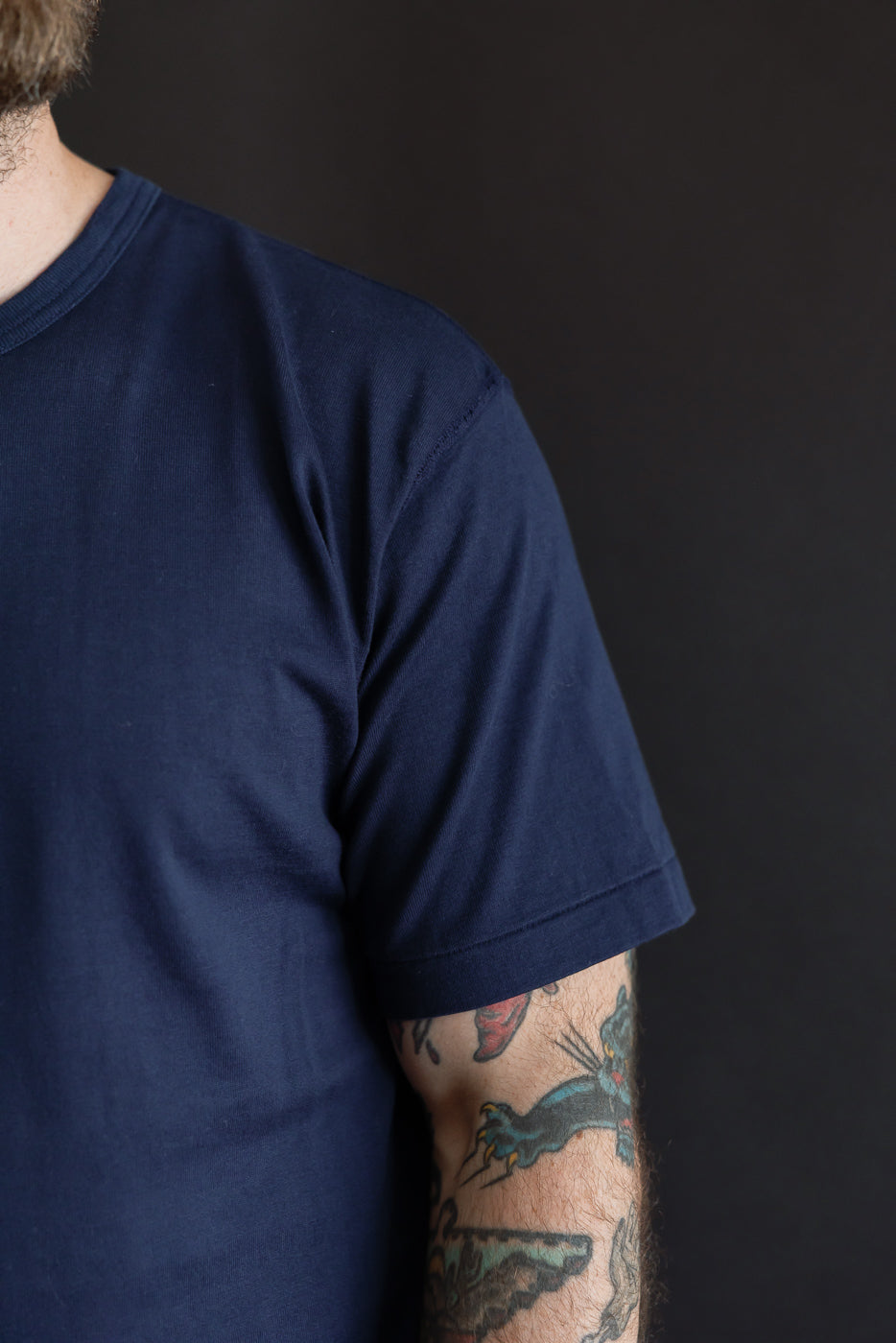 Close-up of the left sleeve and side of a navy t-shirt on a male model, 5'9