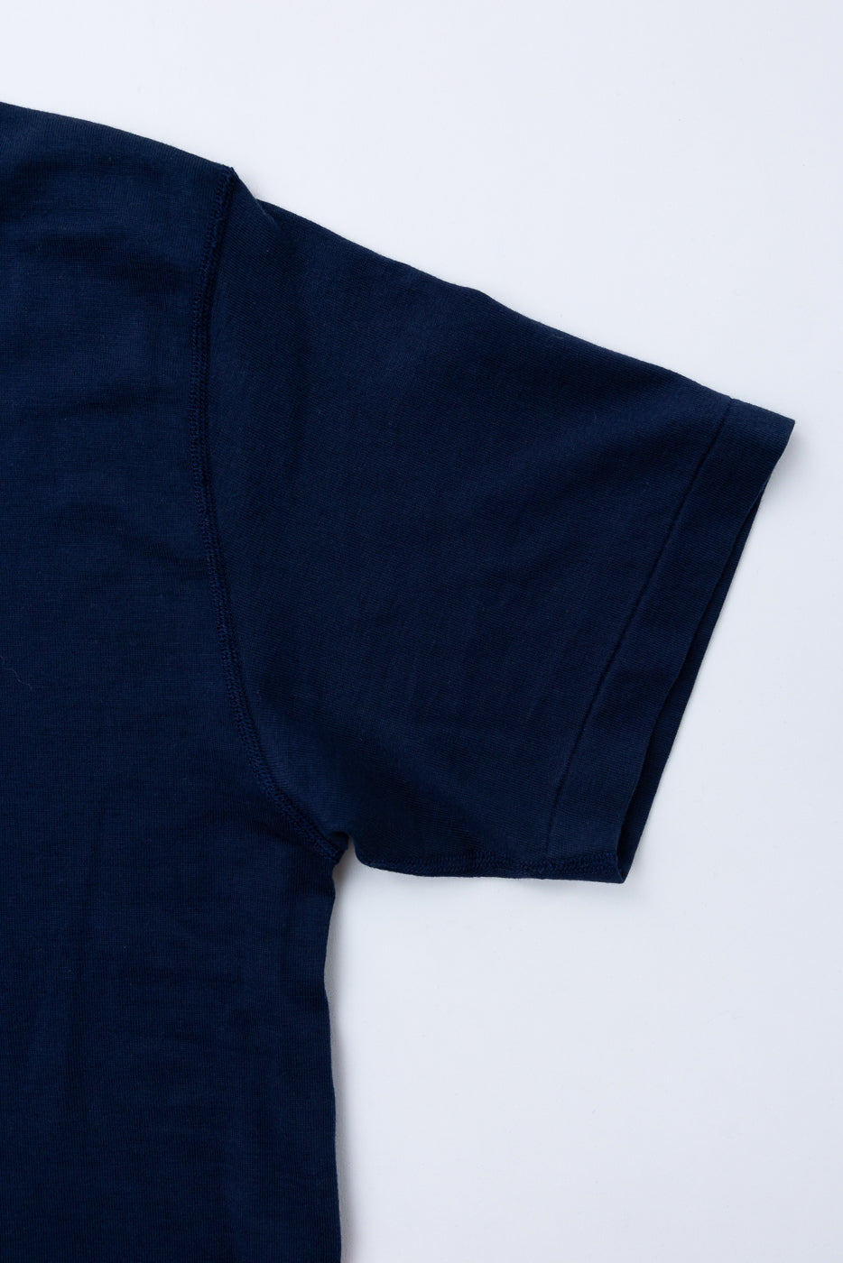 Close-up of the front sleeve and shoulder of a navy blue t-shirt showing fabric texture.